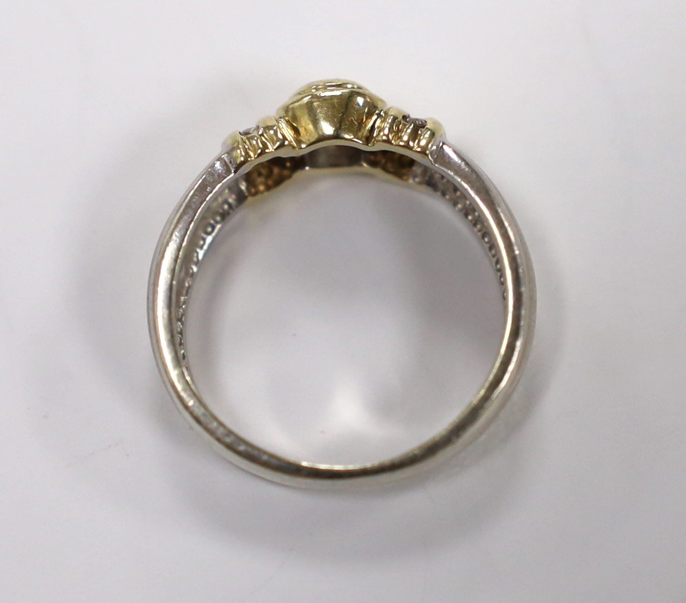 A modern two colour 9ct and collet set single stone diamond set ring, with diamond chip set shoulders, size N, gross weight 4.4 grams.